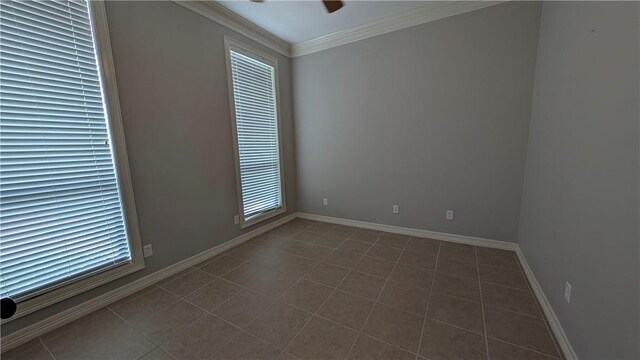 spare room featuring ceiling fan, ornamental molding, dark tile patterned flooring, and baseboards