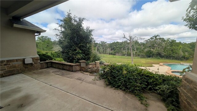 view of patio / terrace with an outdoor pool, an outdoor hot tub, and a wooded view