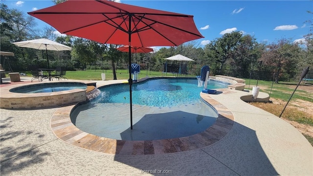 view of swimming pool with an in ground hot tub, pool water feature, a patio, and a lawn