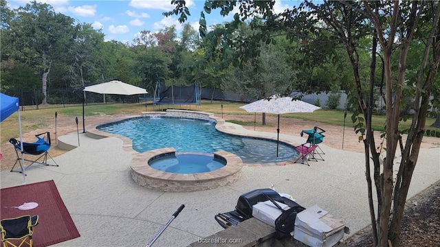 view of swimming pool featuring a trampoline, an in ground hot tub, and a patio