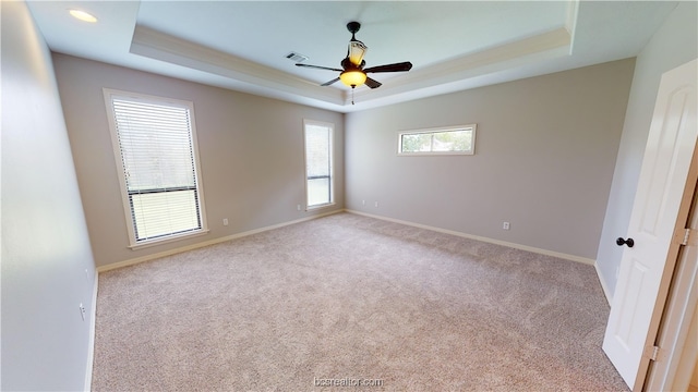 unfurnished room featuring ceiling fan, light carpet, and a tray ceiling