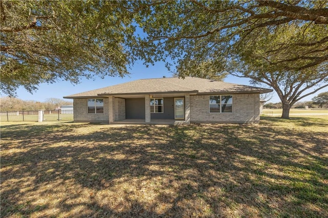 view of front of house featuring brick siding, a patio area, a front lawn, and fence