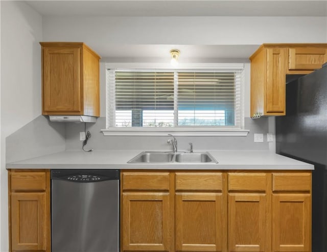 kitchen with a sink, stainless steel dishwasher, light countertops, and freestanding refrigerator