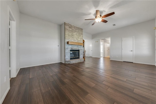 unfurnished living room with a brick fireplace, baseboards, dark wood-style flooring, and ceiling fan