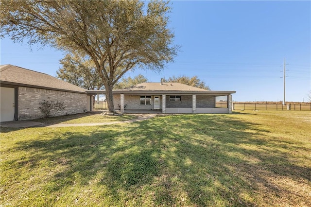 rear view of property with a yard, fence, and brick siding