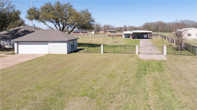 view of yard with a carport, concrete driveway, a garage, and fence