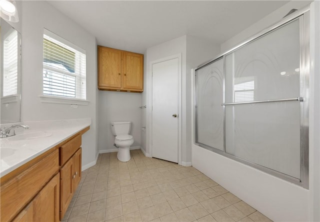 bathroom with vanity, baseboards, tile patterned flooring, toilet, and combined bath / shower with glass door