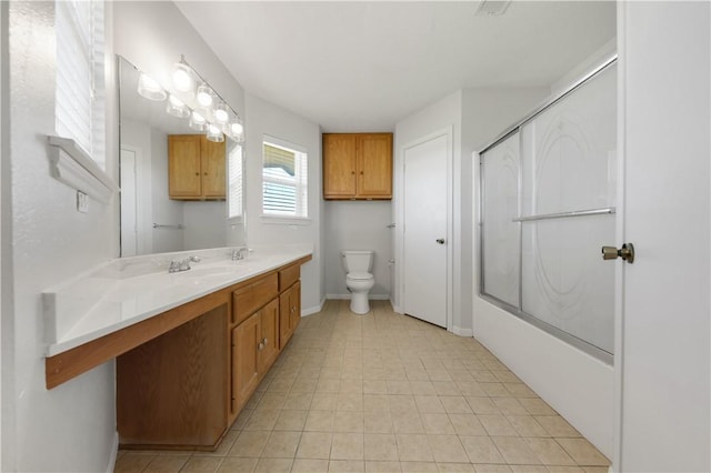 full bath featuring toilet, vanity, baseboards, and shower / bath combination with glass door