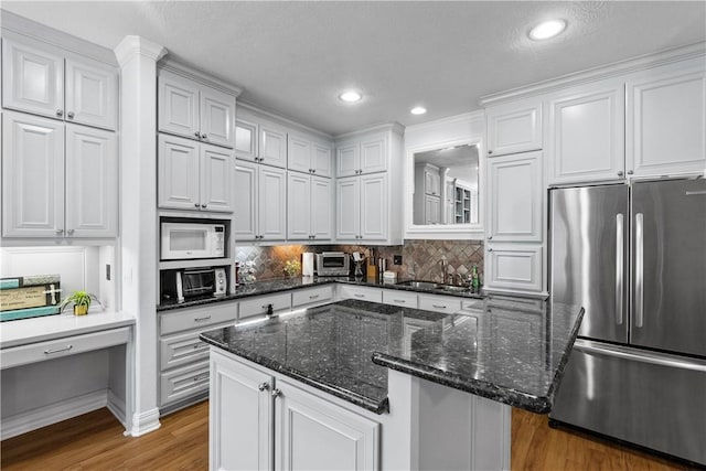 17265 Fm 2154th Rd, College Station, TX 77845 - kitchen with stainless steel fridge, white microwave, wood finished floors, white cabinetry, and recessed lighting