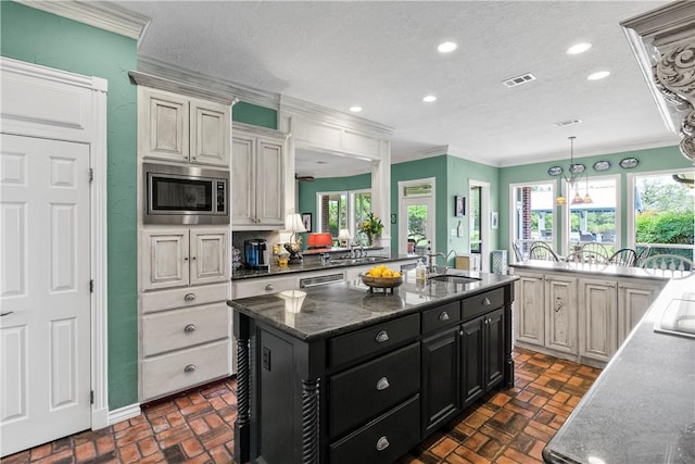 17265 Fm 2154th Rd, College Station, TX 77845 - kitchen featuring stainless steel microwave, brick floors, a sink, dark cabinets, and crown molding
