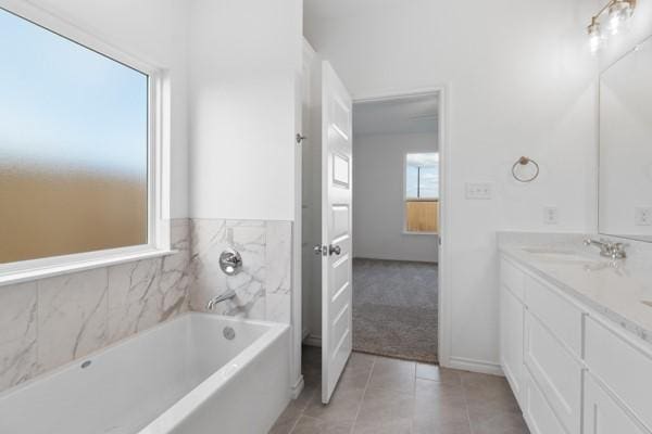 bathroom featuring double vanity, tile patterned floors, a garden tub, and a sink