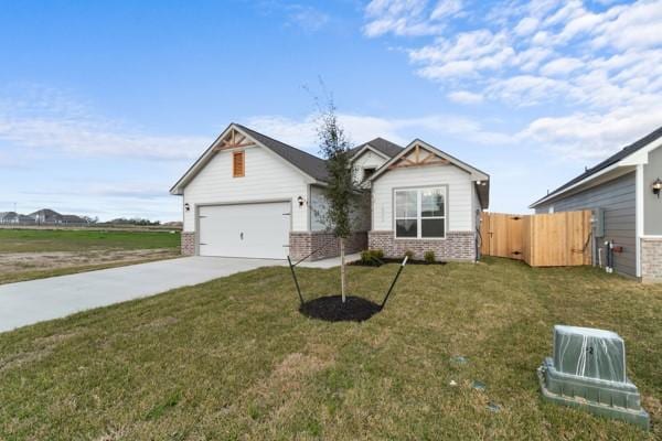 view of front of home featuring a front lawn, fence, brick siding, an attached garage, and driveway