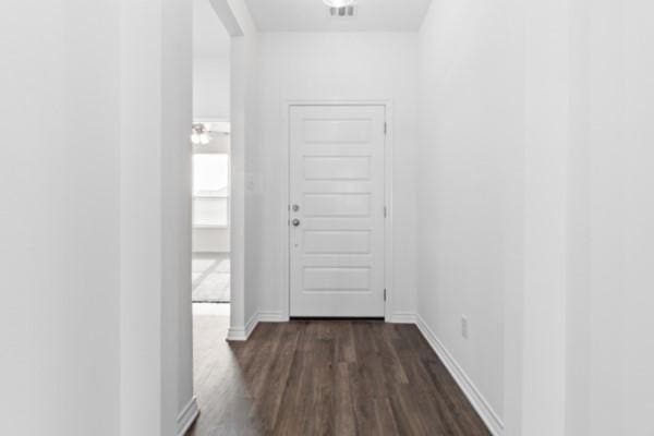 corridor featuring baseboards, dark wood-style flooring, and visible vents