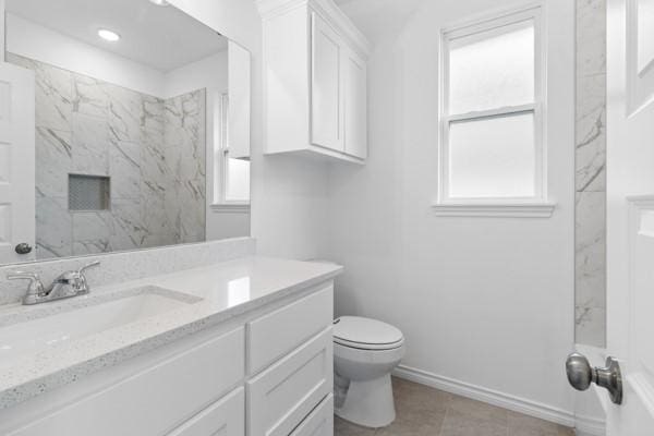 bathroom with baseboards, tile patterned floors, vanity, toilet, and a marble finish shower