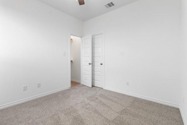 unfurnished bedroom with baseboards, visible vents, and carpet