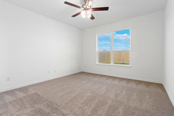 carpeted spare room featuring baseboards and ceiling fan