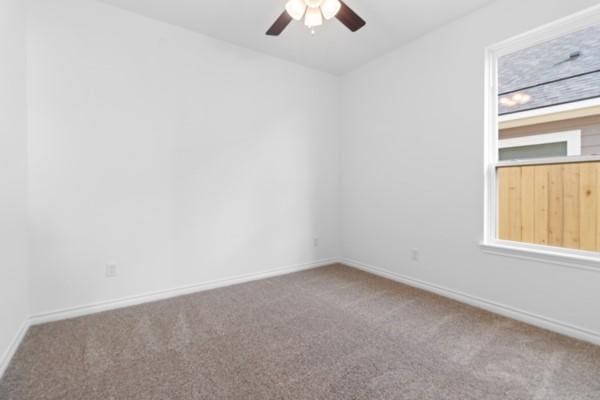 carpeted spare room with baseboards and a ceiling fan