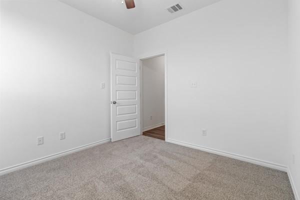 empty room featuring carpet floors, ceiling fan, baseboards, and visible vents