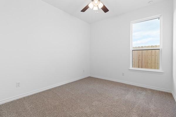 carpeted spare room featuring baseboards and a ceiling fan