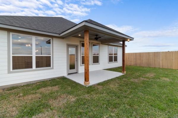 back of property featuring a yard, fence, a ceiling fan, and a patio area