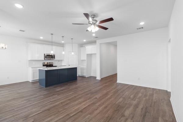 kitchen with white cabinets, stainless steel microwave, ceiling fan with notable chandelier, and range