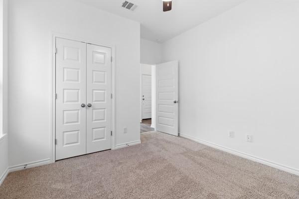 unfurnished bedroom with baseboards, visible vents, carpet, and a closet