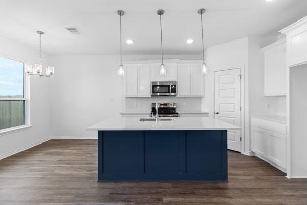 kitchen featuring appliances with stainless steel finishes, a sink, light countertops, a chandelier, and backsplash