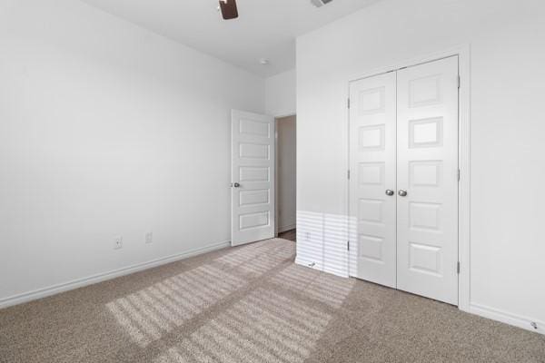 unfurnished bedroom featuring carpet flooring, a ceiling fan, baseboards, and a closet