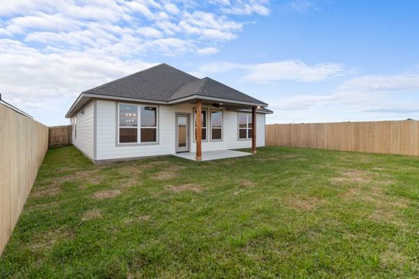 rear view of house with a fenced backyard, a lawn, and a patio area