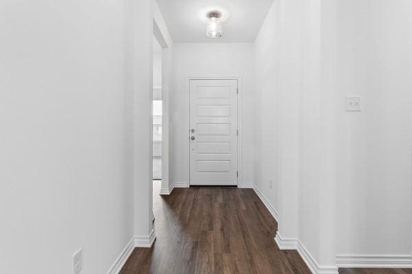 corridor featuring dark wood-style flooring and baseboards