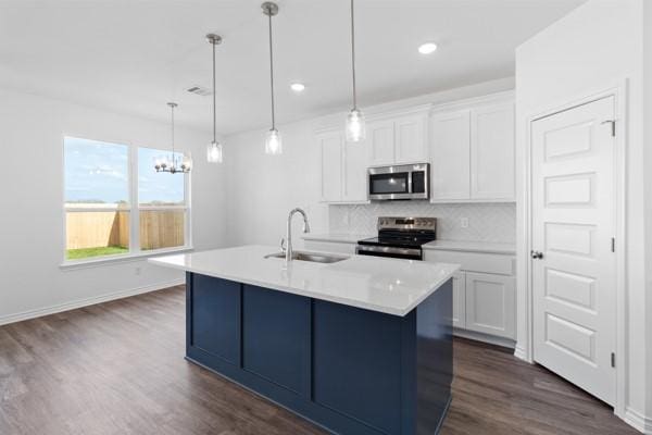 kitchen featuring a sink, stainless steel appliances, white cabinetry, dark wood-type flooring, and backsplash