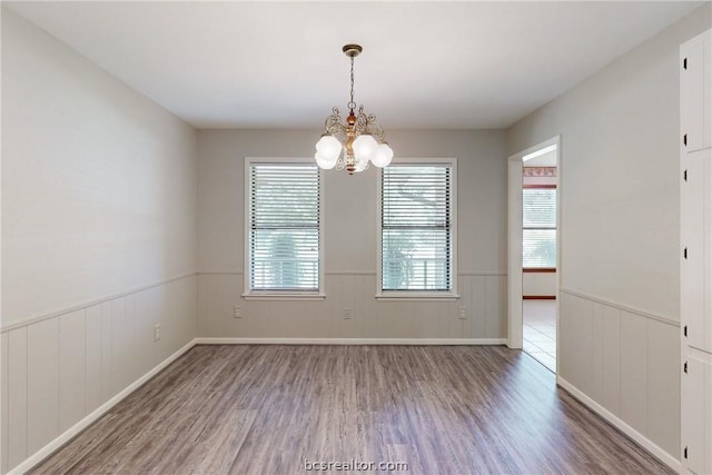 empty room with hardwood / wood-style floors and an inviting chandelier