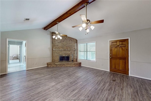 unfurnished living room featuring lofted ceiling with beams, ceiling fan, dark wood-type flooring, and a brick fireplace