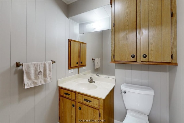 bathroom with vanity, toilet, and wooden walls