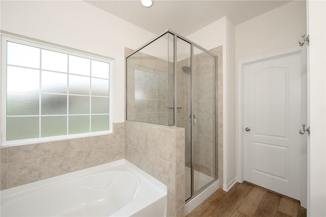 bathroom with hardwood / wood-style flooring and shower with separate bathtub