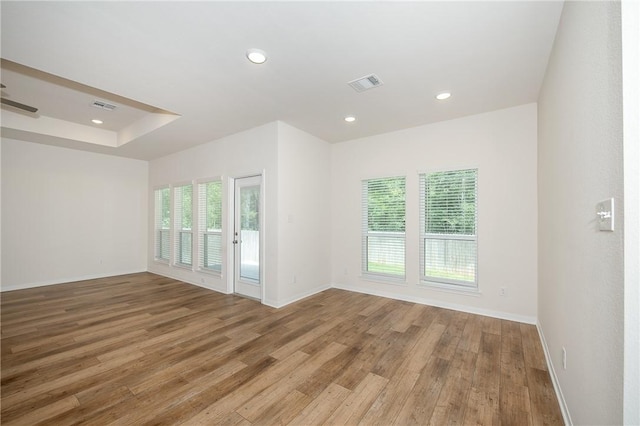 unfurnished room with wood-type flooring and a tray ceiling