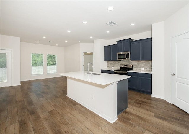 kitchen featuring appliances with stainless steel finishes, sink, dark hardwood / wood-style flooring, backsplash, and an island with sink