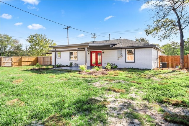 rear view of property with a lawn, a patio area, and central AC