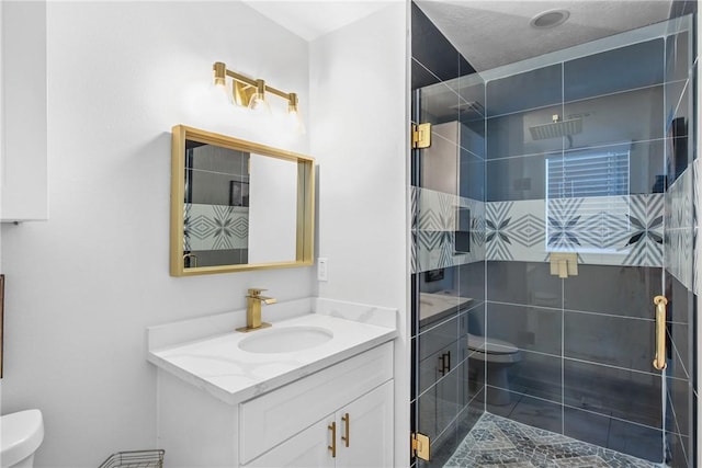 bathroom with a textured ceiling, vanity, toilet, and a shower with door