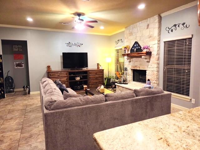 7585 Field Creek Estates Dr, Bryan, TX 77808 - living room with a ceiling fan, crown molding, recessed lighting, a stone fireplace, and baseboards
