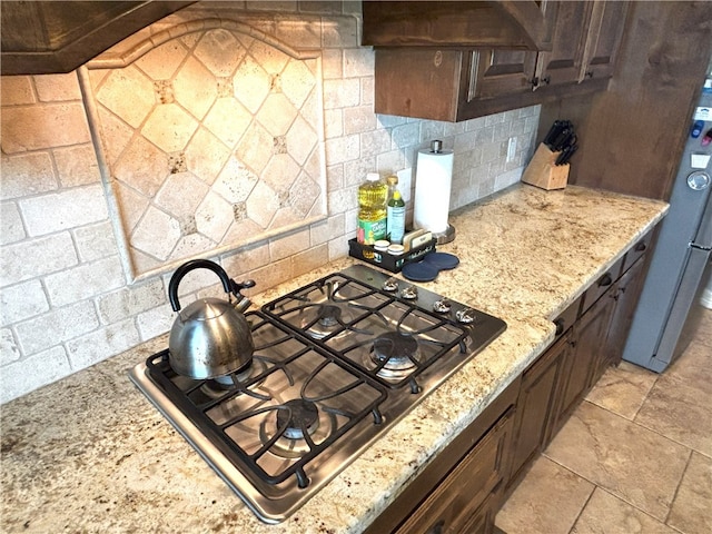 7585 Field Creek Estates Dr, Bryan, TX 77808 - kitchen featuring stainless steel appliances, tasteful backsplash, light stone countertops, and dark brown cabinetry