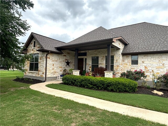 7585 Field Creek Estates Dr, Bryan, TX 77808 - view of front of property featuring stone siding, a front lawn, roof with shingles, and covered porch
