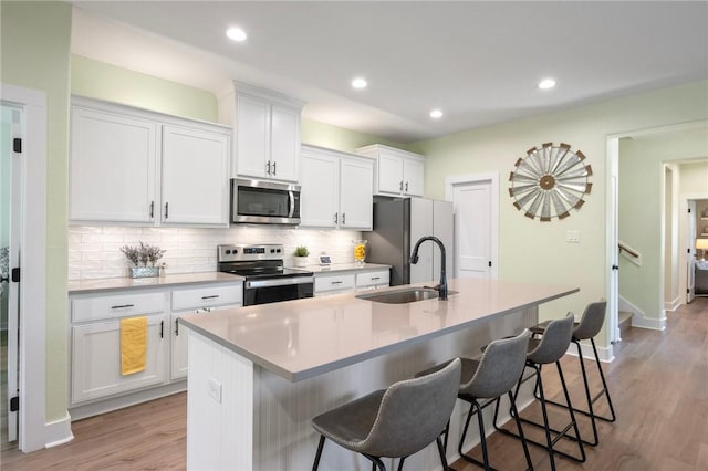 3914 Alamosa St, College Station, TX 77845 - kitchen featuring stainless steel appliances, a sink, a breakfast bar area, a kitchen island with sink, and recessed lighting