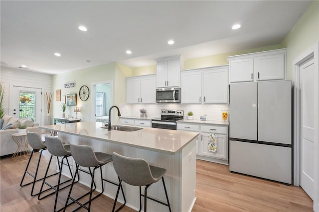 3914 Alamosa St, College Station, TX 77845 - kitchen featuring appliances with stainless steel finishes, a sink, white cabinetry, a kitchen bar, and recessed lighting