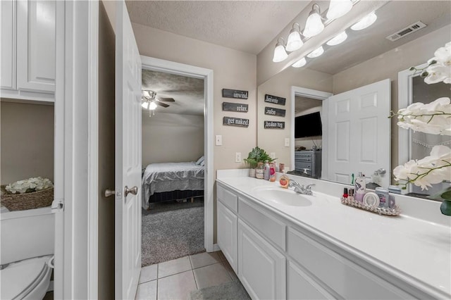 bathroom featuring ceiling fan, tile patterned floors, a textured ceiling, toilet, and vanity