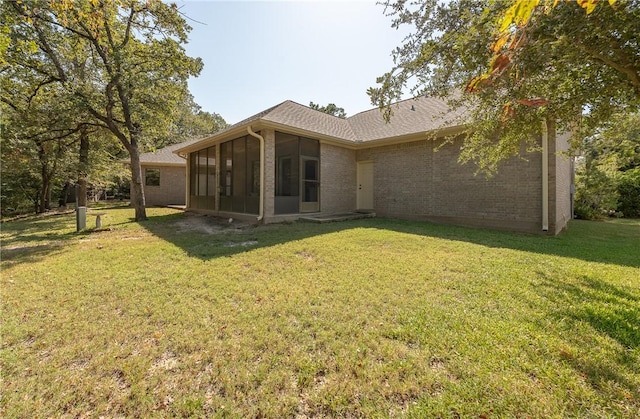 back of property with a lawn and a sunroom