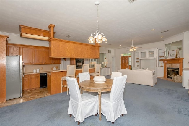 carpeted dining room with crown molding, a fireplace, and ceiling fan with notable chandelier