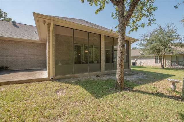 rear view of house with a sunroom, a yard, and central AC