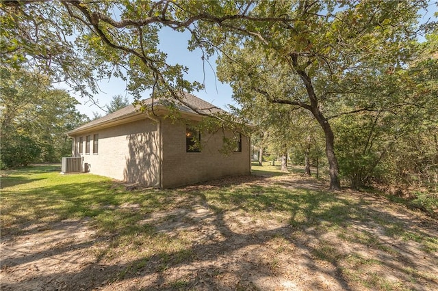 view of side of home featuring a lawn and cooling unit