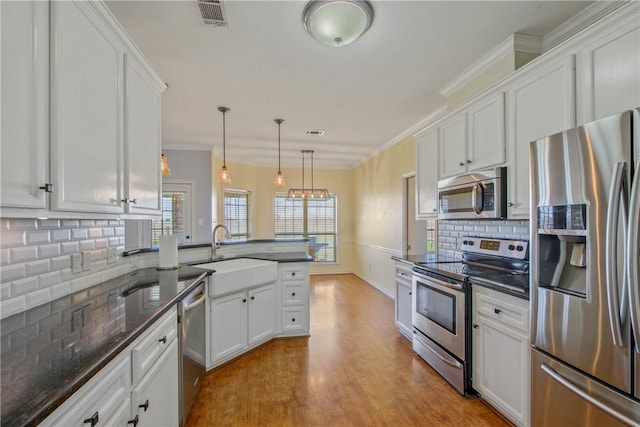 kitchen with visible vents, ornamental molding, appliances with stainless steel finishes, and a sink